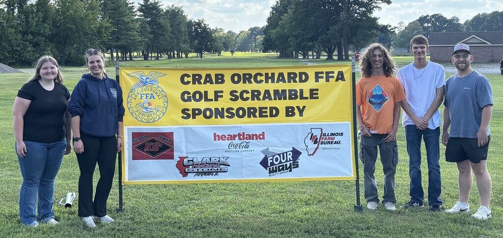2 male high school students, 1 female high school student, 1 female teacher, and 1 male teacher standing by a sign for the FFA Golf Scramble