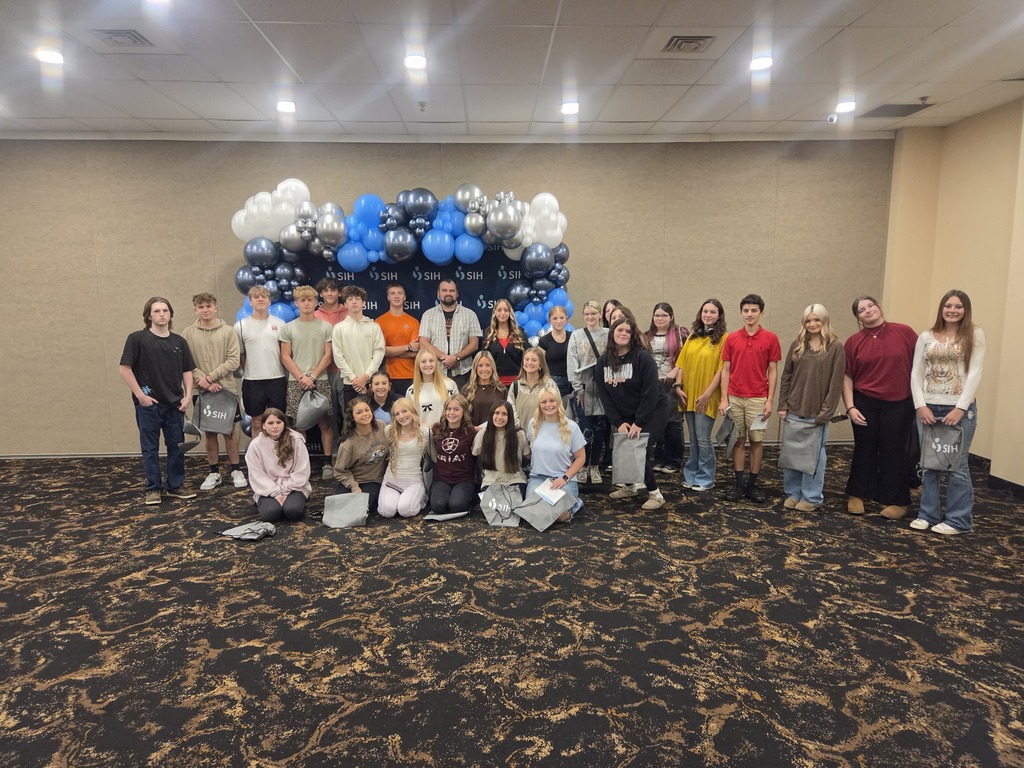 high school students and one adult standing in front of a group of blue balloons