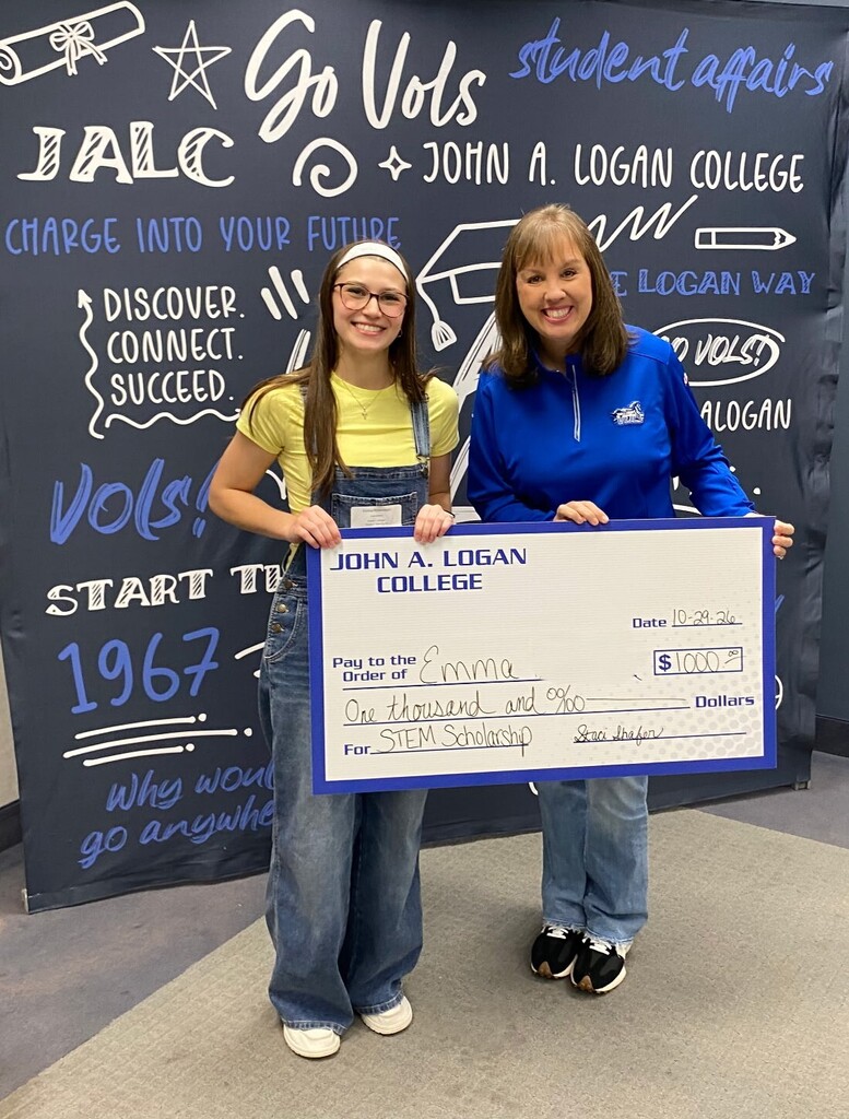 young lady and woman holding a large check in front of a JALC banner