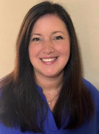 Woman in blue shirt with long brown hair, smiling