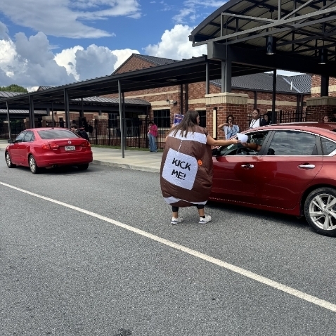 Ms. Austin hands flyers to cars in the carpool line