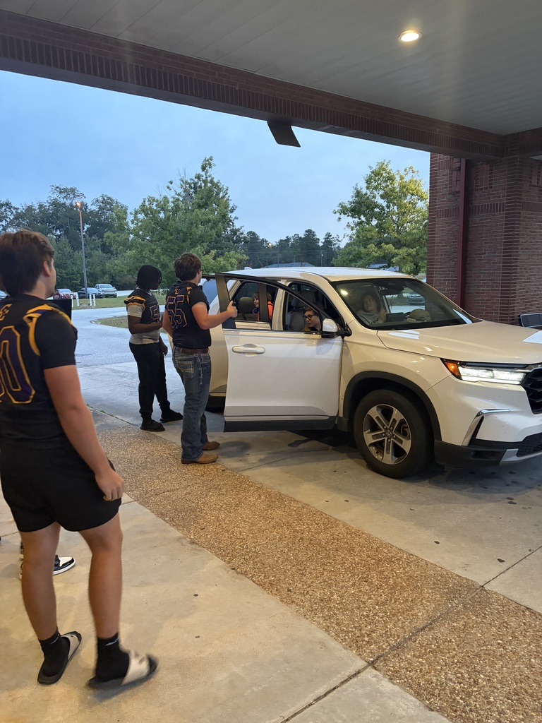 football players greeting students in the drop-off line
