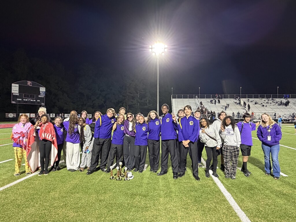 Band members standing on field with trophies