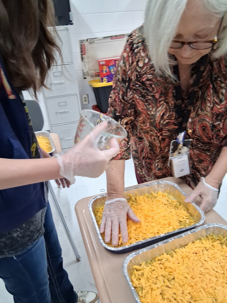 teacher helping student with preparing mac and cheese