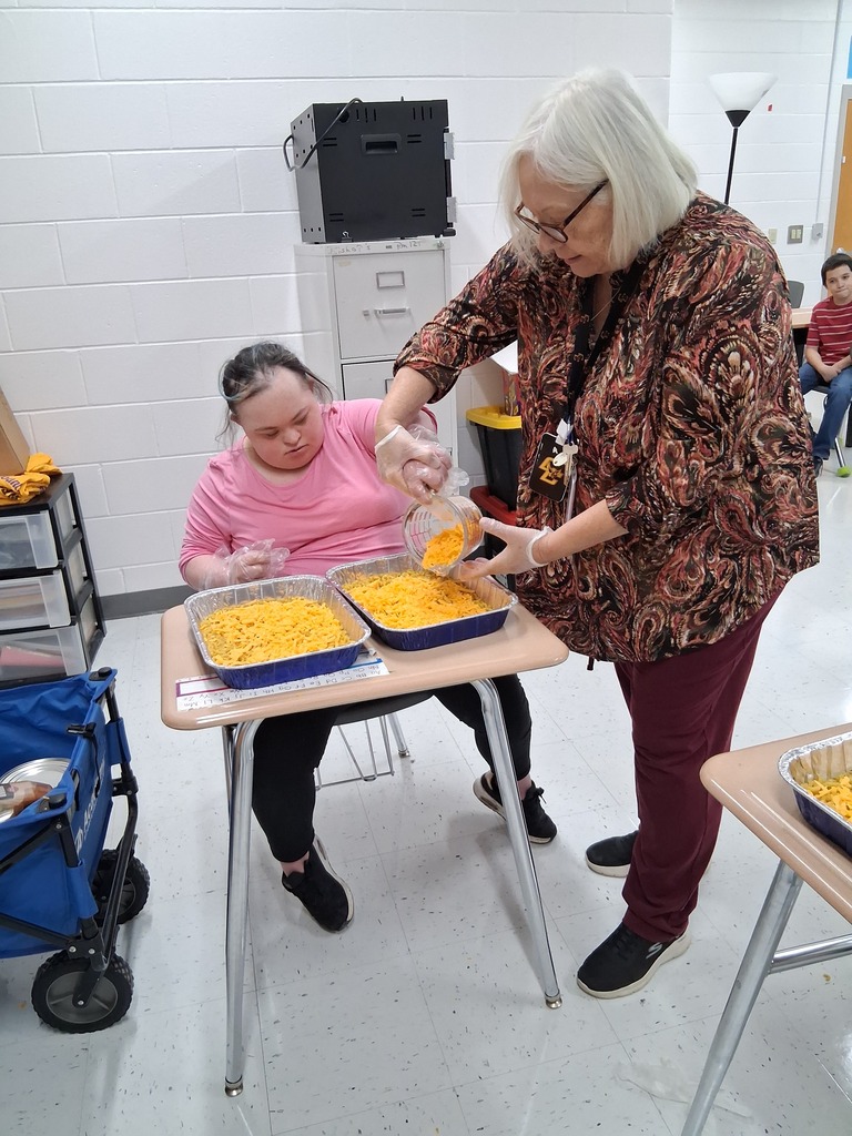 teacher helping student with preparing mac and cheese