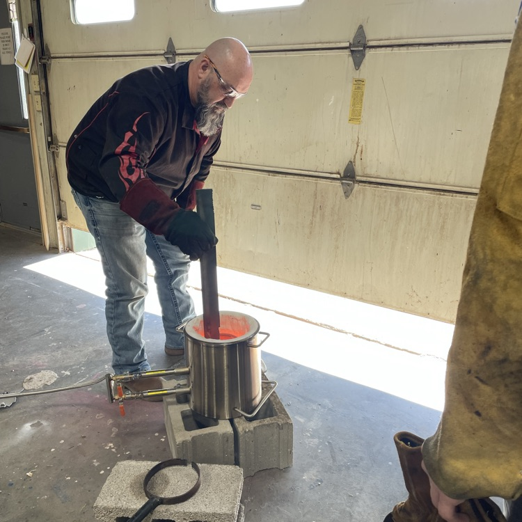 teacher putting metal in the crucible to melt