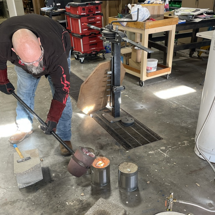 teacher pouring molten metal 