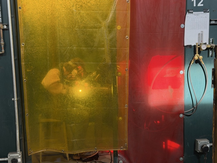 Student welding in the booth.