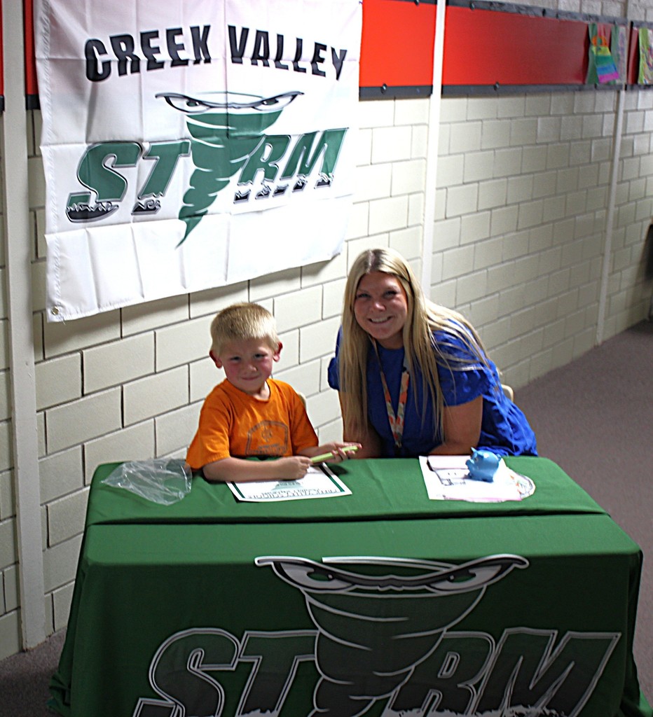 Picture of student signing a certificate to join the kindergarten class next year.