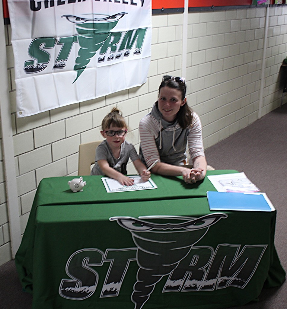 Picture of student signing a certificate to join the kindergarten class next year.