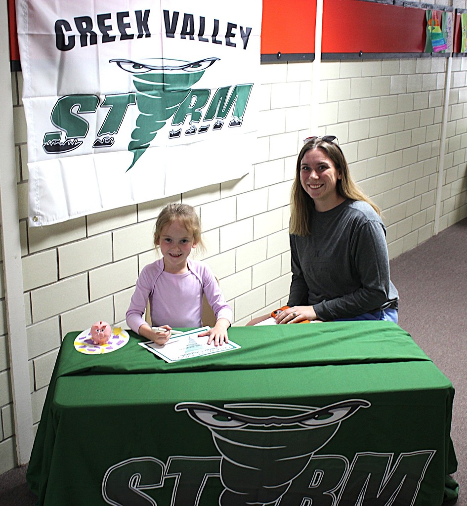 Picture of student signing a certificate to join the kindergarten class next year.
