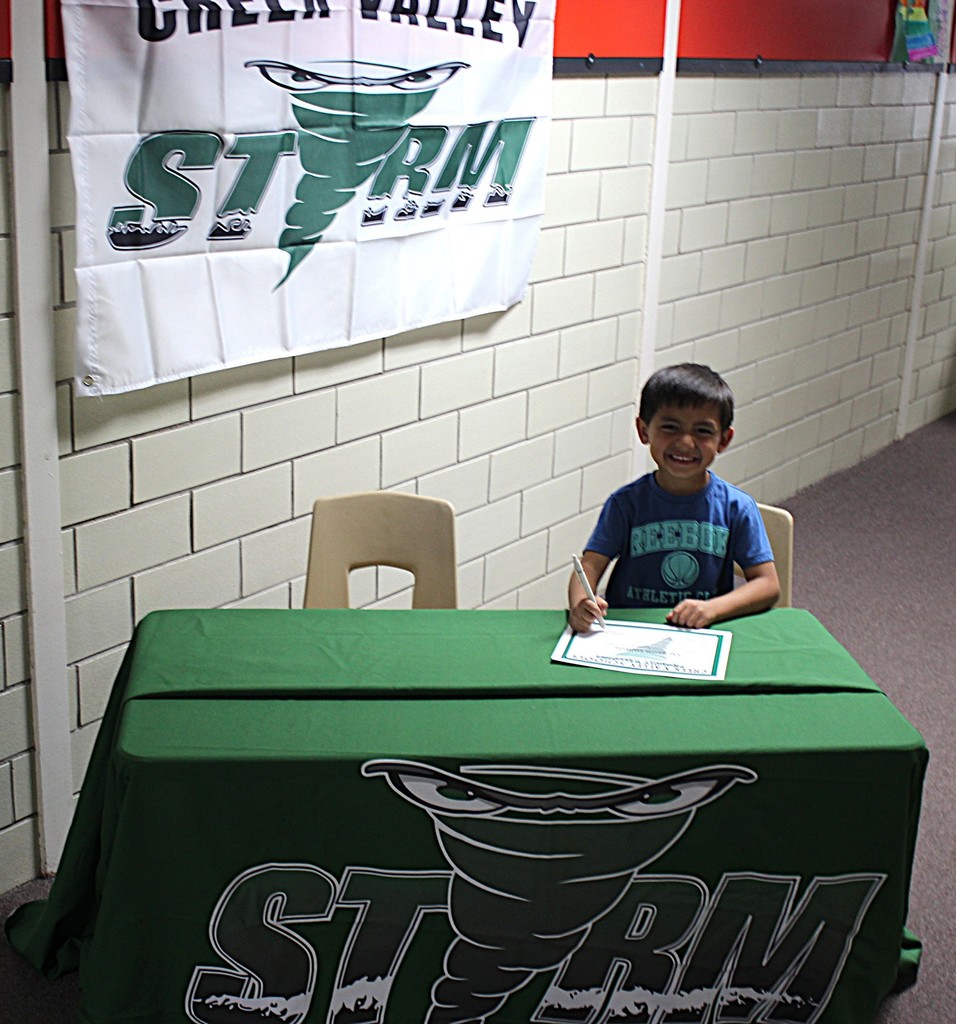 Picture of student signing a certificate to join the kindergarten class next year.