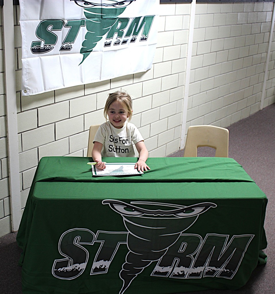 Picture of student signing a certificate to join the kindergarten class next year.