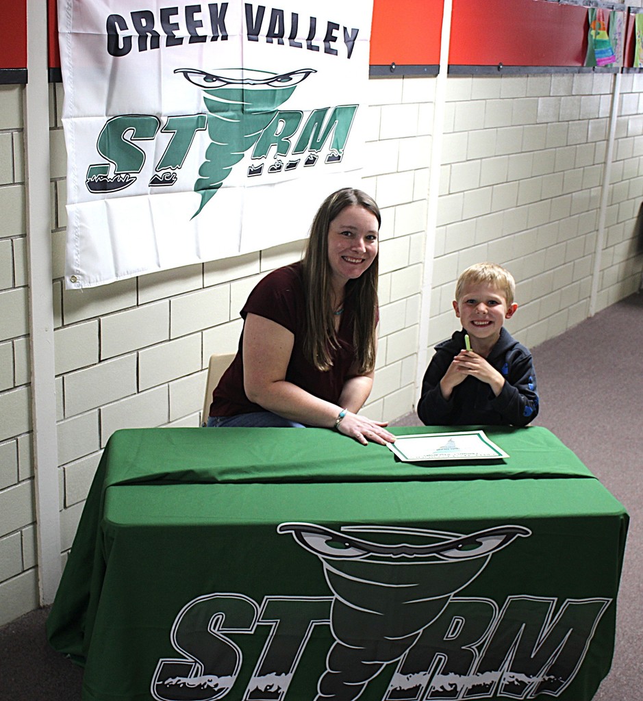 Picture of student signing a certificate to join the kindergarten class next year.