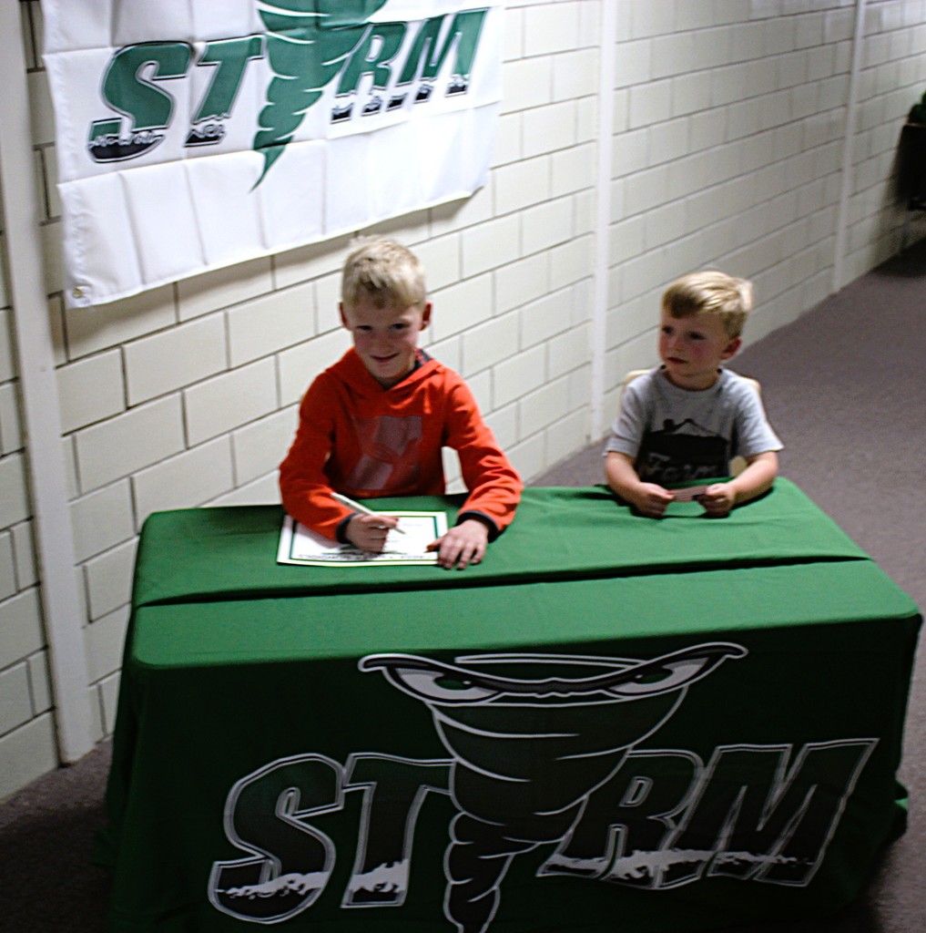 Picture of student signing a certificate to join the kindergarten class next year.