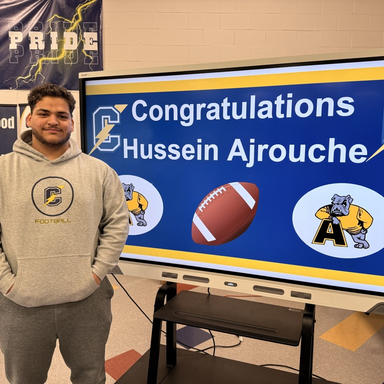 Hussein Ajrouche stands next to the board on his signing day