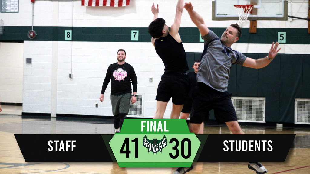 Two men playing basketball, one jumping to shoot, another defending. Final score reads Staff 41, Students 30. Background includes gym walls, a flag, and ventilation.