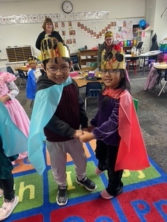 Two students dancing and wearing crowns.
