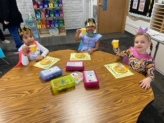 Students sitting at a table wearing crowns.