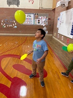 Boy holding a paddle hitting a balloon. 