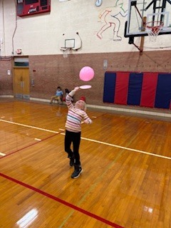 Girl holding a paddle hitting a balloon. 