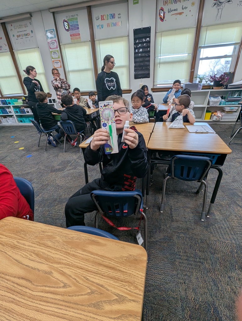 Students and adults in a classroom learning about dental hygiene.