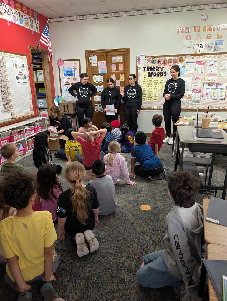 Students and adults in a classroom learning about dental hygiene.