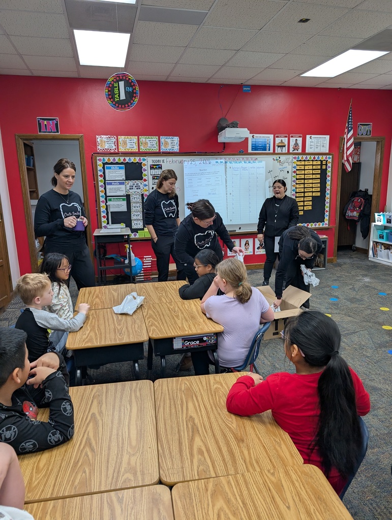 Students and adults in a classroom learning about dental hygiene.