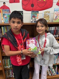 Two students standing and holding books. 