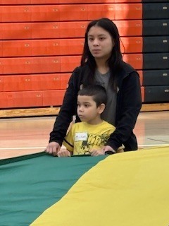 Two students standing by each other holding onto a parachute.