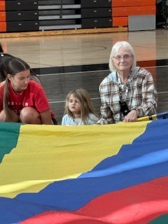 Students sitting and holding onto a parachute.