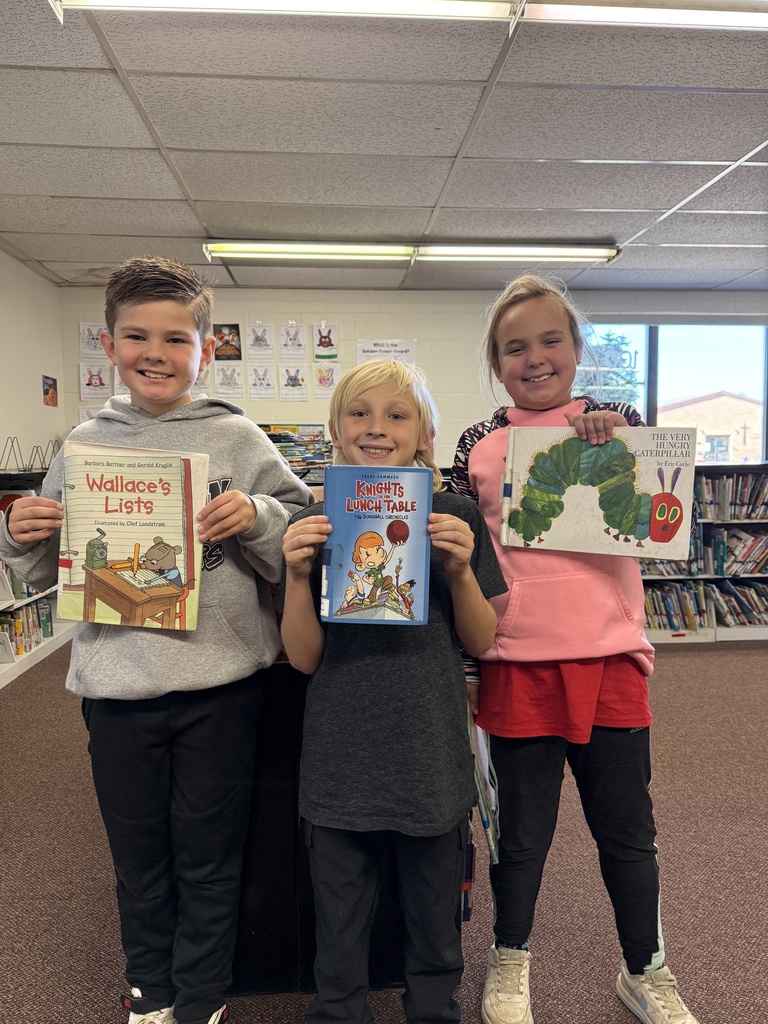 Three students pose with their library books