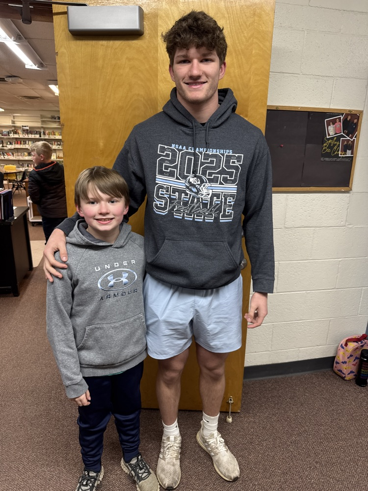 Students posing with their siblings on the track team at High Five Friday