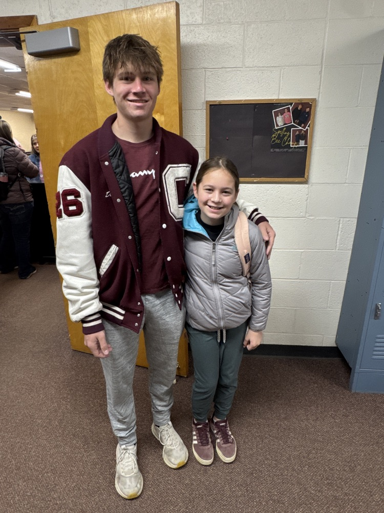 Students posing with their siblings on the track team at High Five Friday