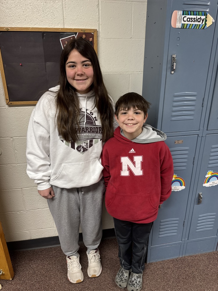 Students posing with their siblings on the track team at High Five Friday