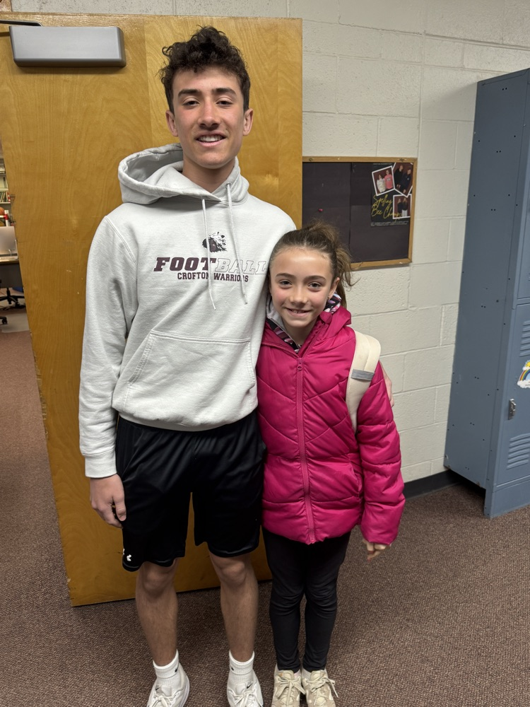 Students posing with their siblings on the track team at High Five Friday