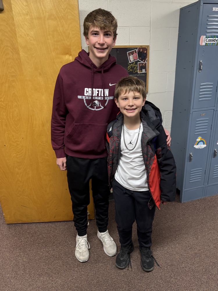 Students posing with their siblings on the track team at High Five Friday