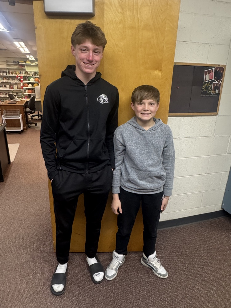 Students posing with their siblings on the track team at High Five Friday