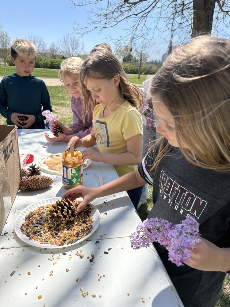 first graders making pine cone bird feeders