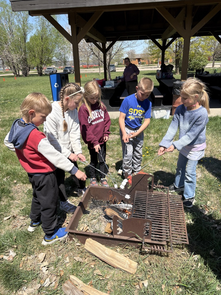 first graders roasting marshmallows around a campfire 