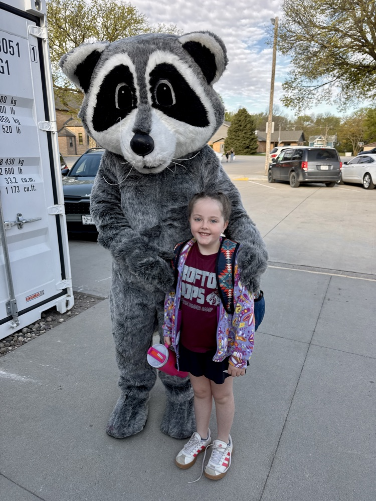 Student posing with members of Lewis & Clark Recreation’s raccoon mascot