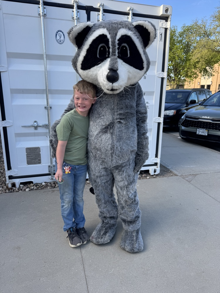 Student posing with members of Lewis & Clark Recreation’s raccoon mascot