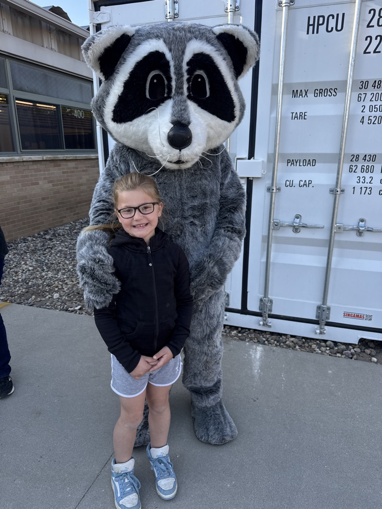 Student posing with members of Lewis & Clark Recreation’s raccoon mascot