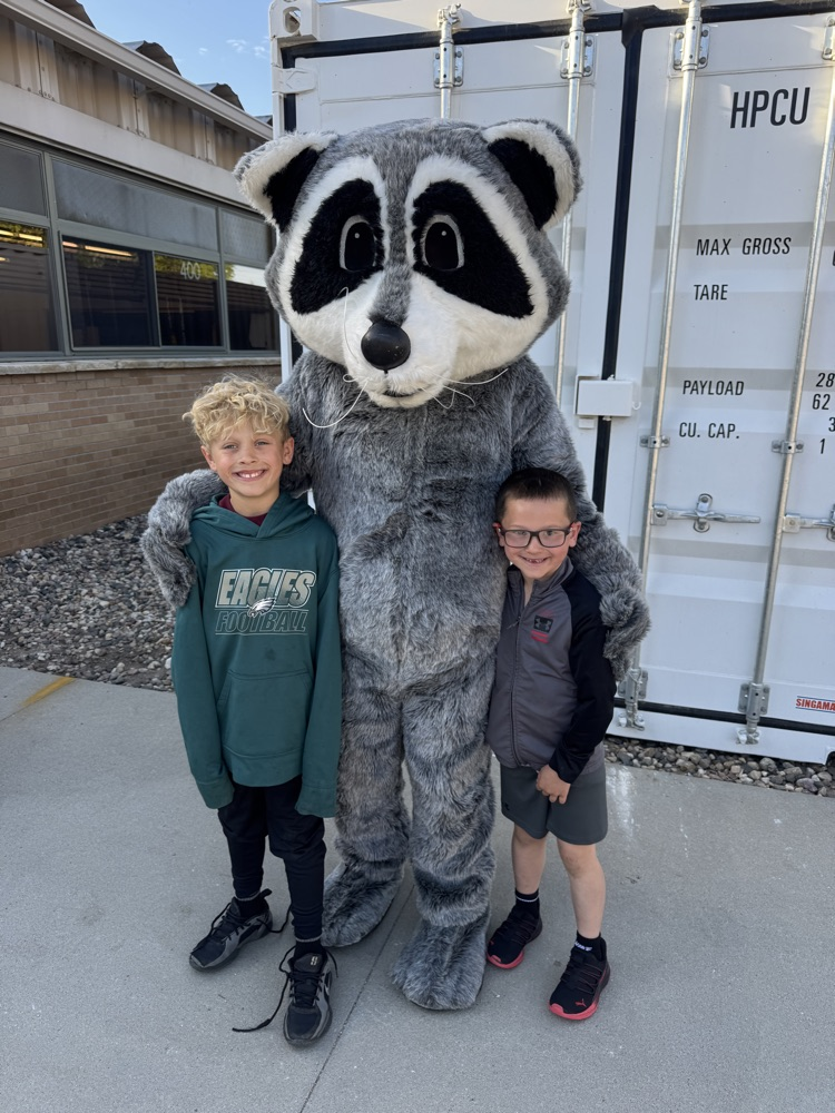 Student posing with members of Lewis & Clark Recreation’s raccoon mascot