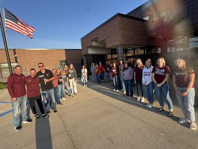Members of Crofton Community Schools are smiling in front of the high school to greet the students 