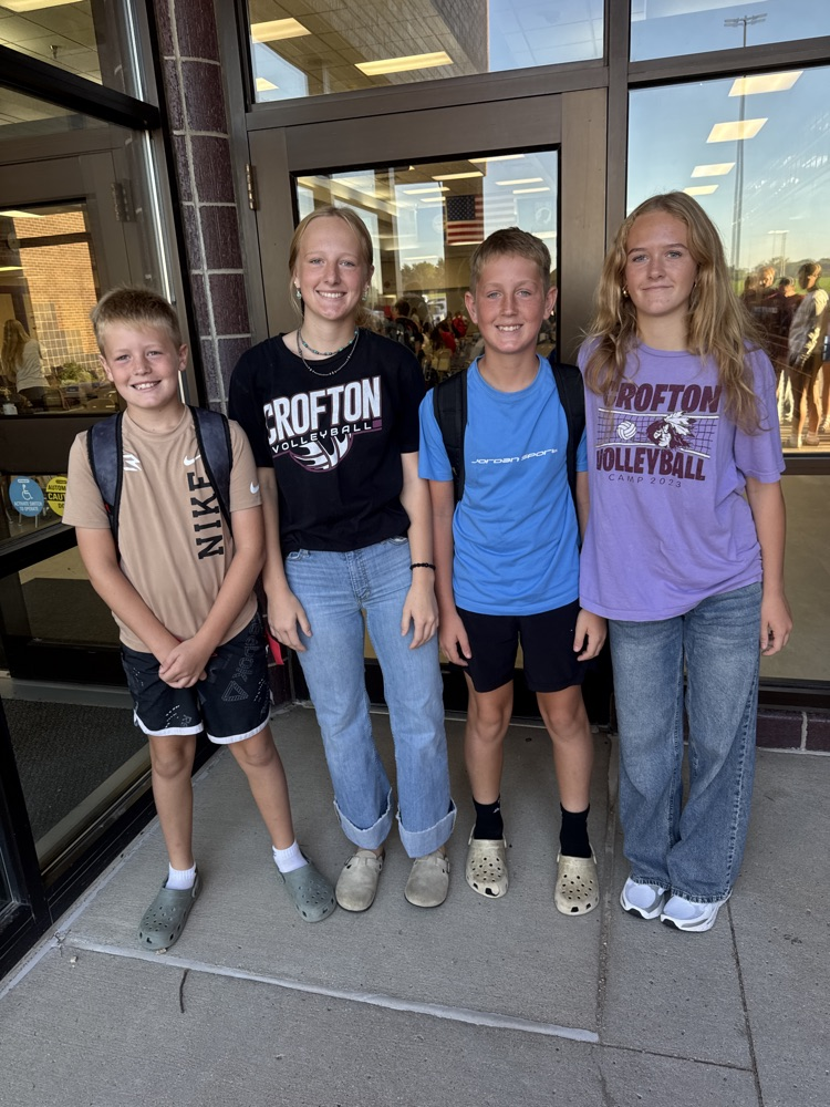 Two volleyball players pose with their younger brothers at High Five Friday 