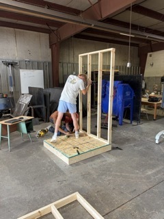 Construction Trade students fastening a wall to the rest of their structure 