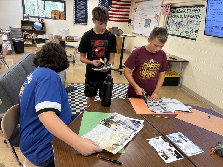 Students searching magazines for examples.