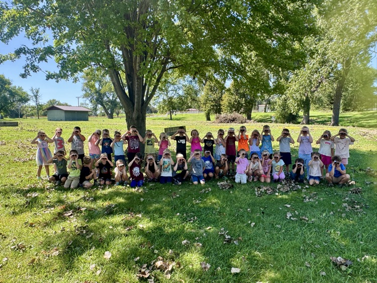Kindergarteners using their binoculars to help them find living things at the park