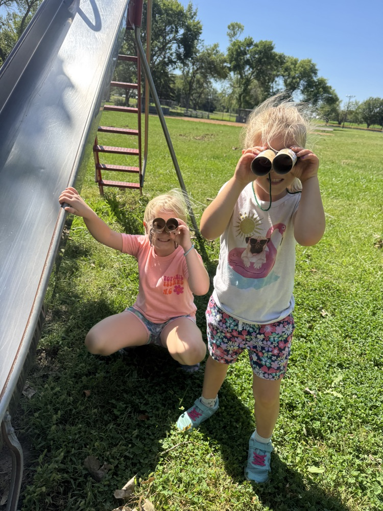Kindergarteners using their binoculars to help them find living things at the park